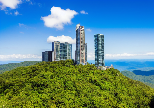 a tall building on top of a lush green hillside with a blue sky in the background and a few clouds in the sky